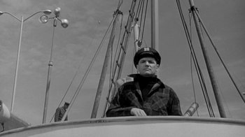 Movie still from “The Slender Thread” (1965), directed by Sydney Pollack – A man wearing a hat sitting on a boat; Medium shot, Low angle