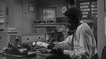 Movie still from “The Slender Thread” (1965), directed by Sydney Pollack – A black and white photo of a man working at a desk; Medium shot, Low angle