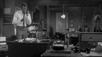 Movie still from “The Slender Thread” (1965), directed by Sydney Pollack – A man talking on a phone in a room; Medium shot, High angle