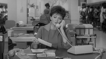 Movie still from “The Slender Thread” (1965), directed by Sydney Pollack – An older woman sitting at a desk talking on the phone; Medium shot, High angle