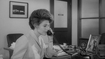 Movie still from “The Slender Thread” (1965), directed by Sydney Pollack – A woman sitting at a desk talking on a phone; Medium shot, Low angle