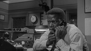 Movie still from “The Slender Thread” (1965), directed by Sydney Pollack – A man sitting at a table talking on a phone; Close Up shot, Low angle