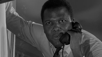 Movie still from “The Slender Thread” (1965), directed by Sydney Pollack – A black and white photo of a man talking on a phone; Close Up shot, Low angle
