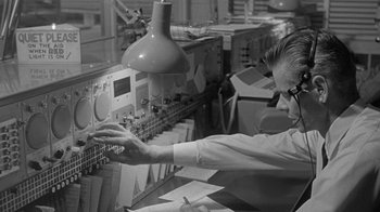Movie still from “The Slender Thread” (1965), directed by Sydney Pollack – A man in a lab coat working in a lab; Medium shot, Low angle