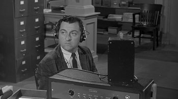 Movie still from “The Slender Thread” (1965), directed by Sydney Pollack – A man wearing headphones sitting in front of an amplifier; Medium shot, High angle