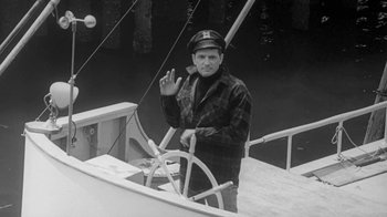 Movie still from “The Slender Thread” (1965), directed by Sydney Pollack – An older man in plaid shirt and hat standing on a boat; Medium shot, High angle