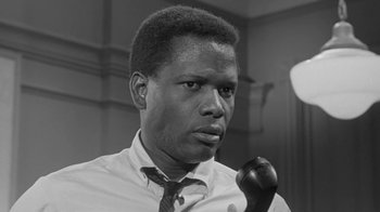 Movie still from “The Slender Thread” (1965), directed by Sydney Pollack – A black and white photo of a man holding a pipe in his mouth; Close Up shot, Low angle