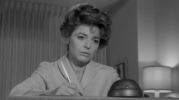 Movie still from “The Slender Thread” (1965), directed by Sydney Pollack – A woman sitting at a table with a pen in her hand; Close Up shot, Low angle