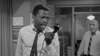 Movie still from “The Slender Thread” (1965), directed by Sydney Pollack – A black and white photo of a man holding a phone up to his ear; Close Up shot, Low angle