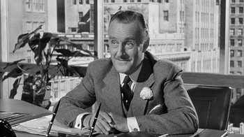 Movie still from “The Solid Gold Cadillac” (1956), directed by Richard Quine – An old black and white photo of a man sitting at a table; Close Up shot, Low angle