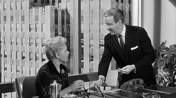 Movie still from “The Solid Gold Cadillac” (1956), directed by Richard Quine – An old photo of a man and a woman talking to each other; Medium shot, Over the shoulder angle