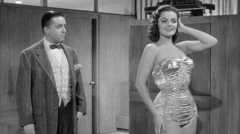 Movie still from “The Solid Gold Cadillac” (1956), directed by Richard Quine – A man and a woman standing next to each other; Medium shot, Over the shoulder angle