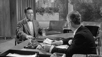 Movie still from “The Solid Gold Cadillac” (1956), directed by Richard Quine – A man and a woman sitting at a table; Medium shot, Over the shoulder angle