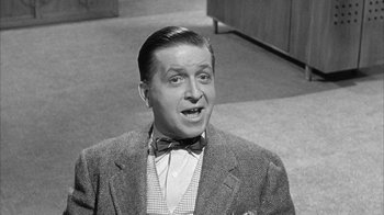 Movie still from “The Solid Gold Cadillac” (1956), directed by Richard Quine – An old photo of a man wearing a suit and bow tie; Close Up shot, Low angle