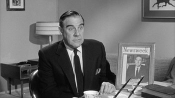 Movie still from “The Solid Gold Cadillac” (1956), directed by Richard Quine – An older man sitting at a table with a cup of coffee; Medium shot, Over the shoulder angle