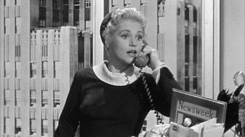 Movie still from “The Solid Gold Cadillac” (1956), directed by Richard Quine – An older woman talking on the phone in a black and white photo; Medium shot, Low angle