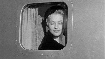 Movie still from “The Solid Gold Cadillac” (1956), directed by Richard Quine – A woman looking out of a window on a plane; Close Up shot, Low angle