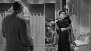 Movie still from “The Solid Gold Cadillac” (1956), directed by Richard Quine – A woman in a black dress hugging another woman in a black dress in front of a mirror; Medium shot, Over the shoulder angle