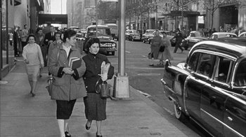 Movie still from “The Solid Gold Cadillac” (1956), directed by Richard Quine – A couple of women walking down a sidewalk; Wide shot, Low angle