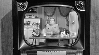 Movie still from “The Solid Gold Cadillac” (1956), directed by Richard Quine – An older woman sitting at a table in front of an old tv; Medium shot, High angle