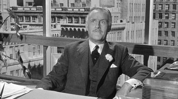 Movie still from “The Solid Gold Cadillac” (1956), directed by Richard Quine – An older man sitting at a table in front of a window; Medium shot, Low angle