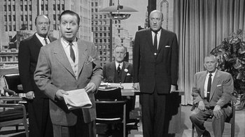 Movie still from “The Solid Gold Cadillac” (1956), directed by Richard Quine – A black and white photo of three men in suits; Medium shot, Over the shoulder angle