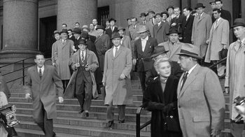 Movie still from “The Solid Gold Cadillac” (1956), directed by Richard Quine – A group of men and women walking down a set of stairs; Wide shot, High angle