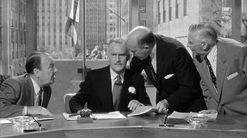 Movie still from “The Solid Gold Cadillac” (1956), directed by Richard Quine – Two men in business suits sitting at a table; Medium shot, Over the shoulder angle