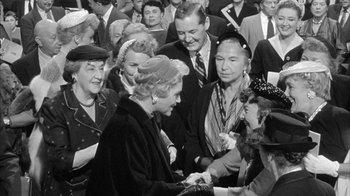 Movie still from “The Solid Gold Cadillac” (1956), directed by Richard Quine – An old black and white photo of a group of people; Medium shot, Over the shoulder angle
