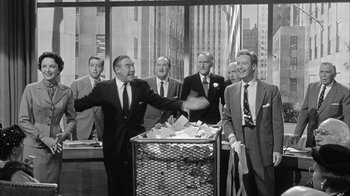 Movie still from “The Solid Gold Cadillac” (1956), directed by Richard Quine – A black and white photo of a group of men in suits and ties; Medium shot, Over the shoulder angle