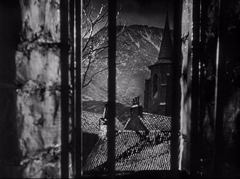 Movie still from “The Song of Bernadette” (1943), directed by Henry King – A view of a church through a window of a building; Extreme Wide shot, High angle