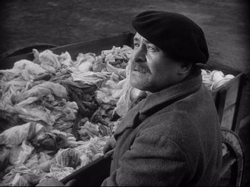 Movie still from “The Song of Bernadette” (1943), directed by Henry King – An old man sitting in front of a pile of garbage; Medium shot, High angle