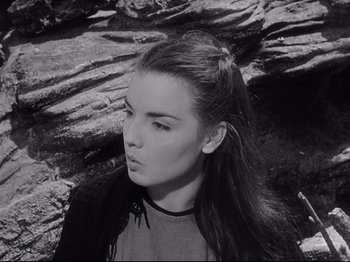 Movie still from “The Song of Bernadette” (1943), directed by Henry King – A woman with long hair is standing in front of rocks; Close Up shot, High angle