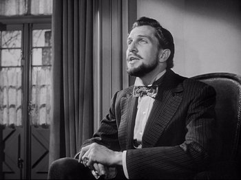 Movie still from “The Song of Bernadette” (1943), directed by Henry King – Black and white photograph of a man wearing a suit and bow tie; Close Up shot, Low angle