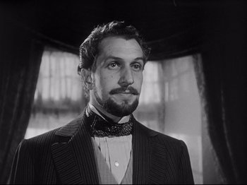 Movie still from “The Song of Bernadette” (1943), directed by Henry King – A black and white photo of a man in a suit; Close Up shot, Low angle