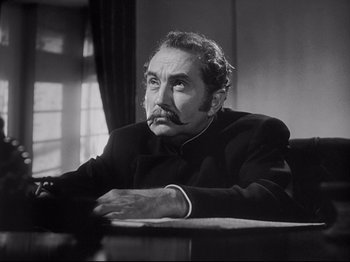 Movie still from “The Song of Bernadette” (1943), directed by Henry King – An older man sitting at a table in a room; Close Up shot, Low angle