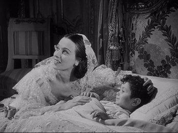 Movie still from “The Song of Bernadette” (1943), directed by Henry King – An old photo of a woman and a boy in a bed; Medium shot, High angle