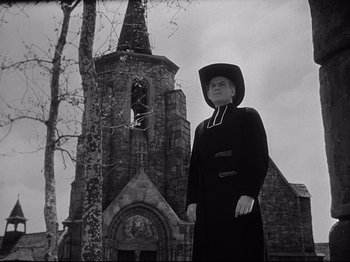 Movie still from “The Song of Bernadette” (1943), directed by Henry King – A man standing in front of an old church; Medium shot, Low angle