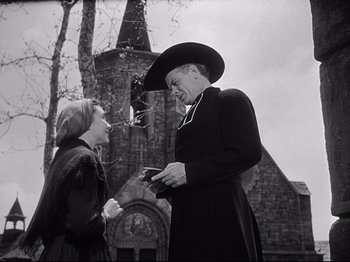 Movie still from “The Song of Bernadette” (1943), directed by Henry King – A woman and a man talking outside of a church; Medium shot, Low angle