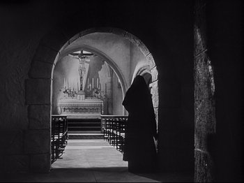 Movie still from “The Song of Bernadette” (1943), directed by Henry King – An old man is standing in a tunnel in front of a church; Wide shot, Low angle