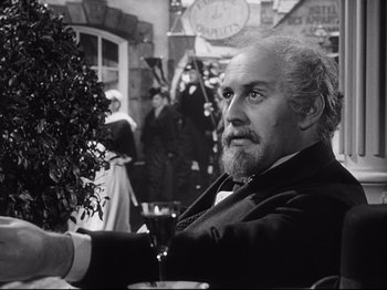 Movie still from “The Song of Bernadette” (1943), directed by Henry King – An older man sitting at a table holding a glass of wine; Close Up shot, Over the shoulder angle