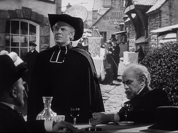 Movie still from “The Song of Bernadette” (1943), directed by Henry King – A man in a black hat and a man in a cowboy hat; Medium shot, Over the shoulder angle