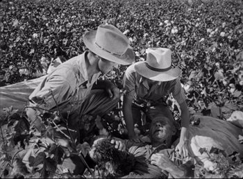 Movie still from “The Southerner” (1945), directed by Jean Renoir – Two men in a field with a man laying on the ground; Medium shot, High angle