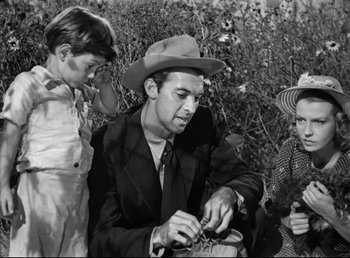 Movie still from “The Southerner” (1945), directed by Jean Renoir – An old black and white photo of a man and two young children; Medium shot, Low angle