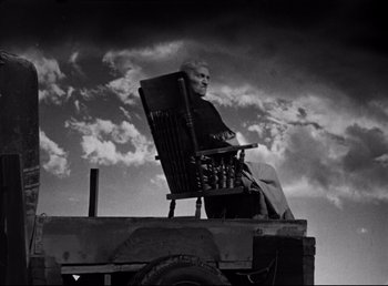 Movie still from “The Southerner” (1945), directed by Jean Renoir – An older man sitting in a chair on top of a truck; Wide shot, Low angle