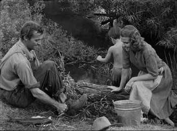 Movie still from “The Southerner” (1945), directed by Jean Renoir – An old black and white photo of a man and a woman and a child; Medium shot, High angle