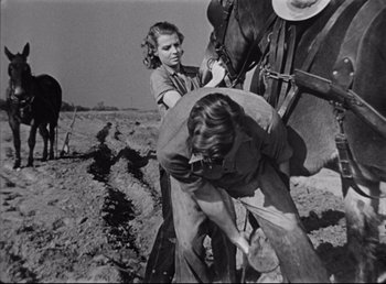 Movie still from “The Southerner” (1945), directed by Jean Renoir – A woman and a girl working on a horse in a field; Medium shot, Low angle