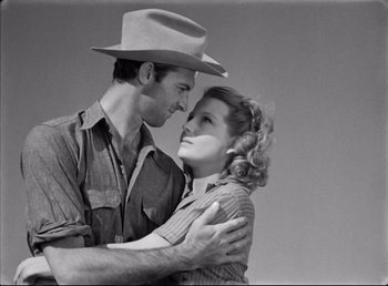 Movie still from “The Southerner” (1945), directed by Jean Renoir – A man and a woman embracing each other in front of a sky background; Medium shot, Low angle