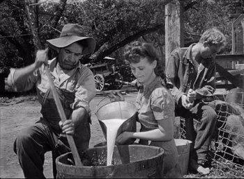 Movie still from “The Southerner” (1945), directed by Jean Renoir – A man and a woman pouring milk into a wooden barrel; Medium shot, High angle