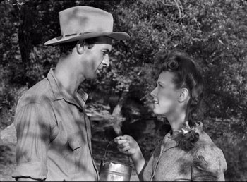 Movie still from “The Southerner” (1945), directed by Jean Renoir – A man and a woman standing next to each other in front of a tree; Medium shot, High angle